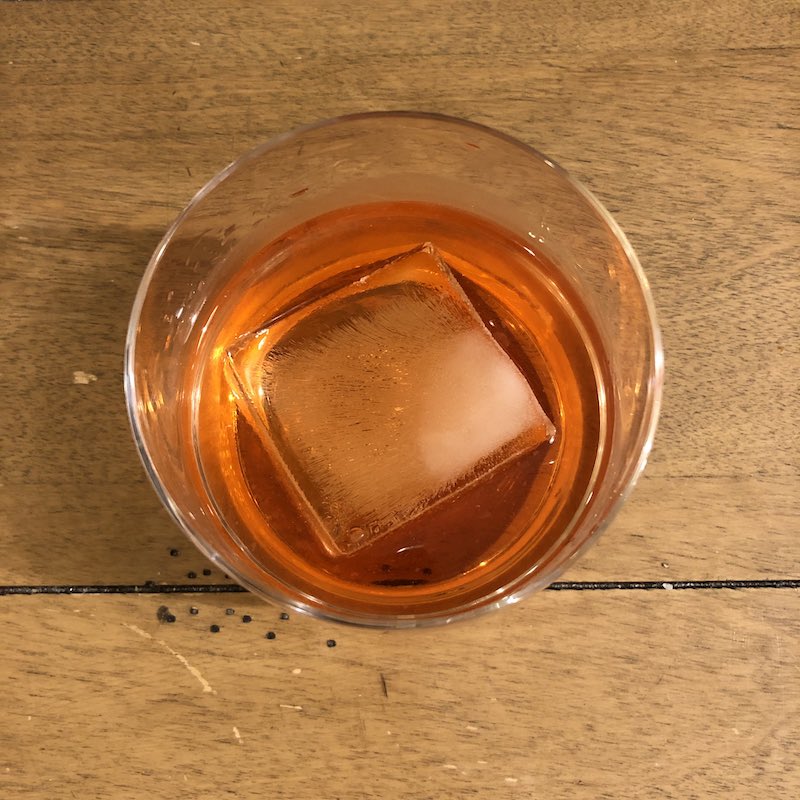orange color whiskey cocktail with large ice