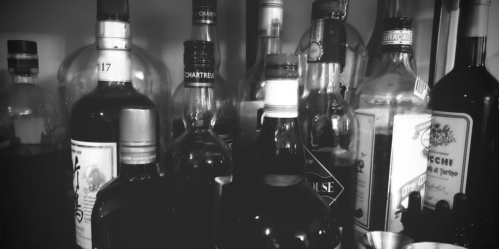 black and white photo of various bottles of alcohol in a bar